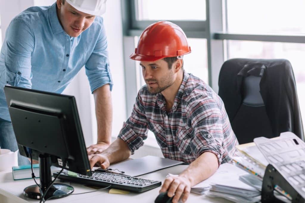 Two construction project mangers looking at a computer in an office