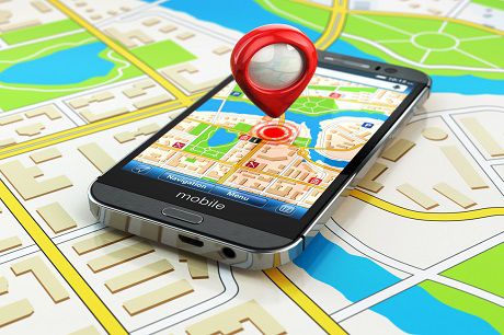Smartphone on a detailed street map displaying a map application with a red pin and navigation circle denoting a specific location, illustrating the GPS technology feature of Jonas Construction software.