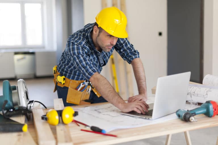 A construction project manager looking at a laptop on a job site