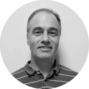 Alt Text: "Smiling middle-aged mechanical contractor in striped polo shirt, displayed within a circular frame against a plain, light-colored background; symbolizing the profession of those who use Jonas Construction Software.