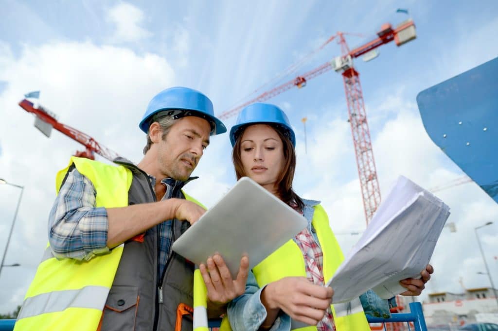 Two construction project managers looking at a tablet at a job site 