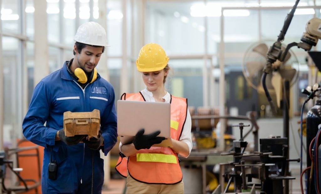 Two construction project managers looking at a laptop at a job site 