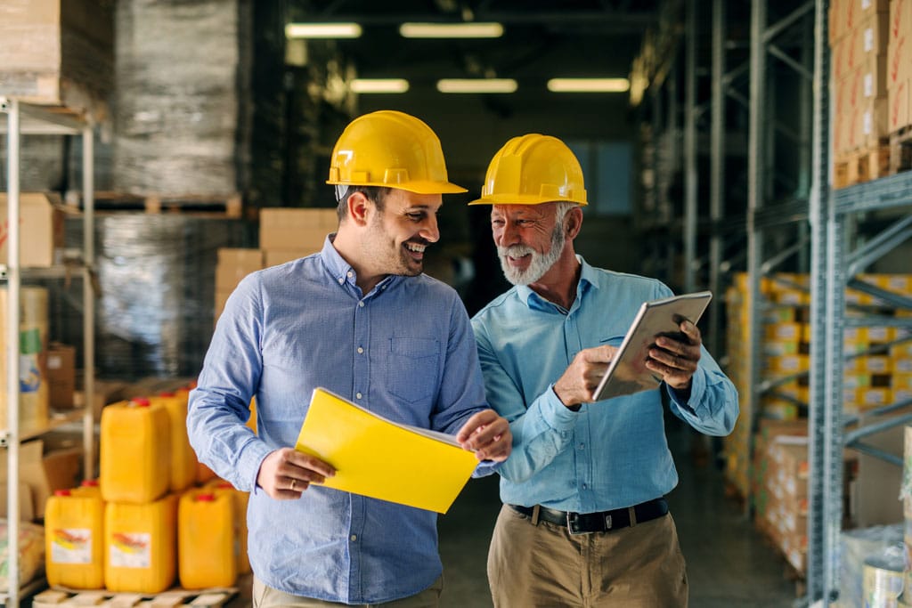 Two mechanical service managers looking at a tablet in a warehouse