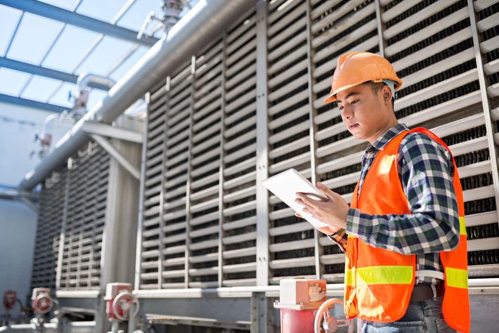 A mechanical service technician looking at a tablet on the field