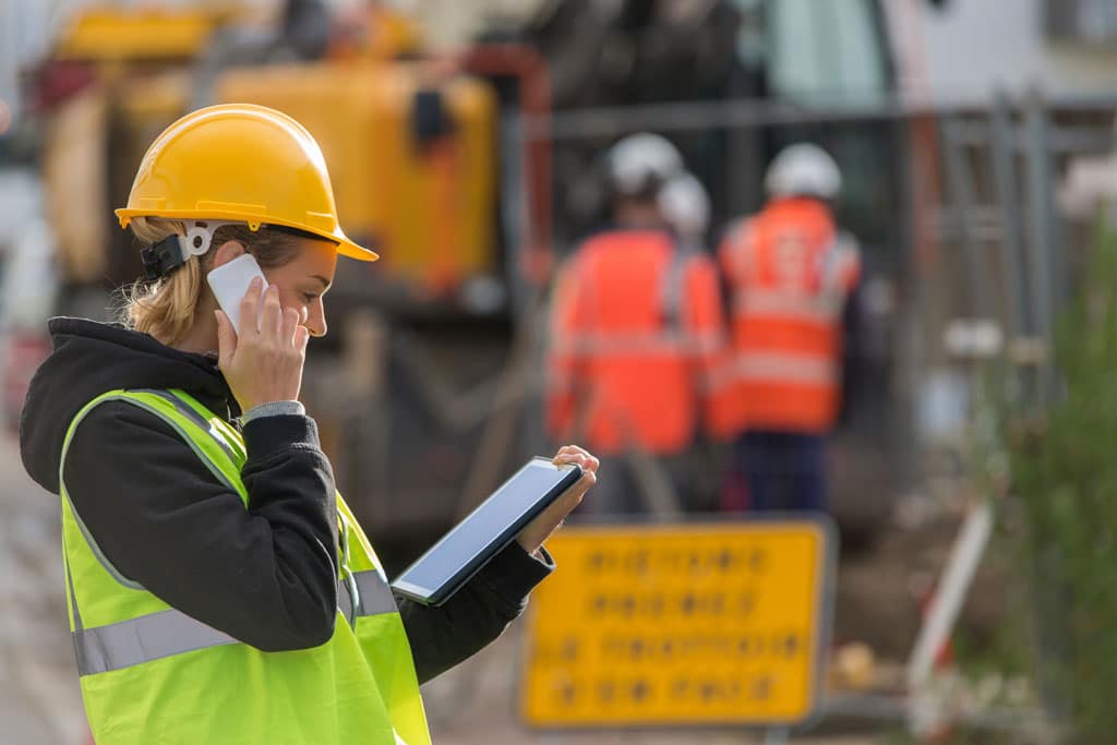 A mechanical service technician looking at a tablet and talking on the phone